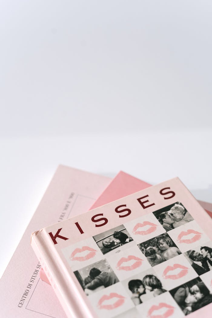 gallery-2 Close-up of stacked books with kiss-themed cover, perfect for romance literature visuals.